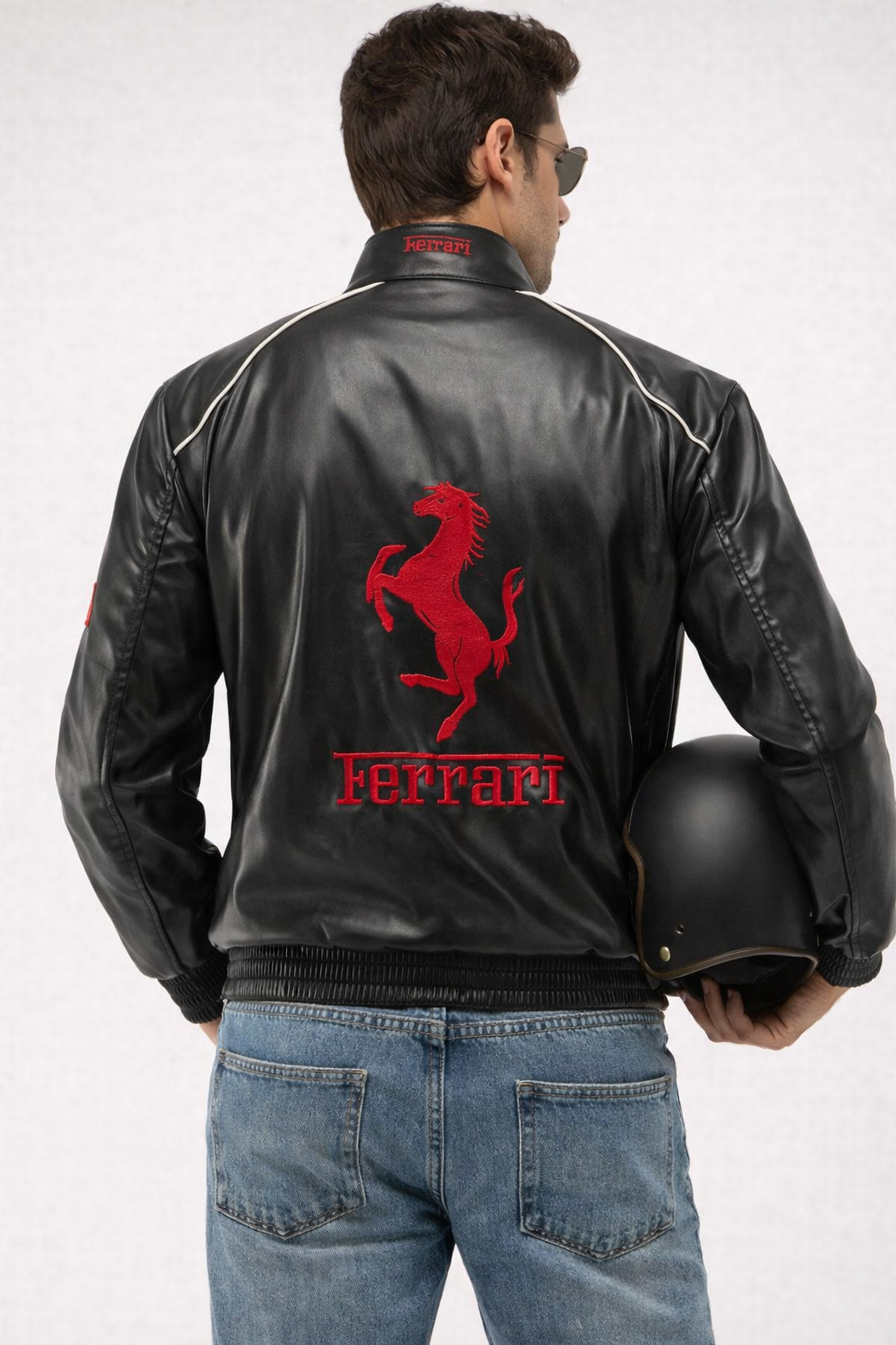 Person wearing a black leather jacket with Ferrari logo and holding a helmet on a white background