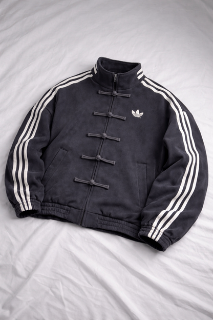 Black Adidas jacket with white stripes on a gray background