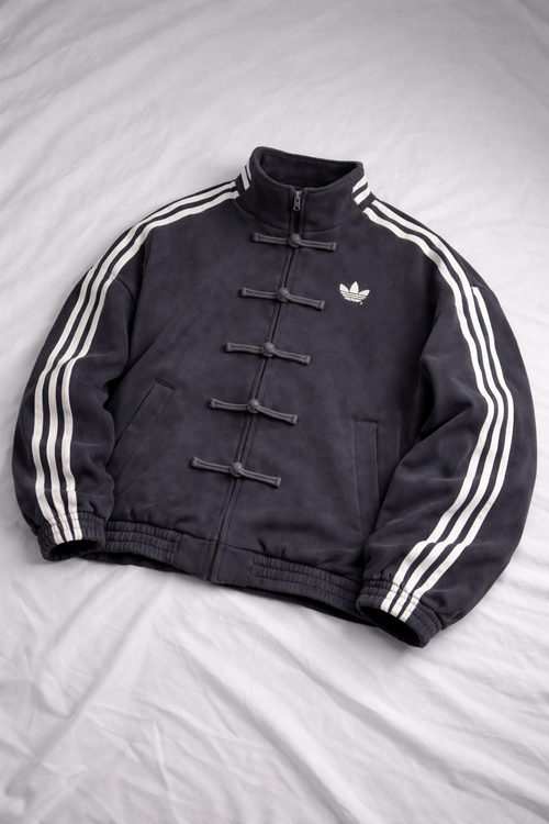 Black Adidas jacket with white stripes on a gray background