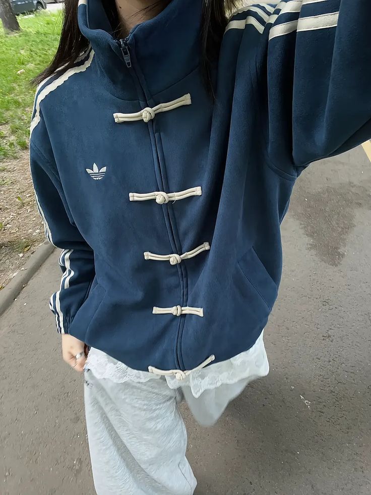 Person wearing a blue jacket with white accents on a sidewalk