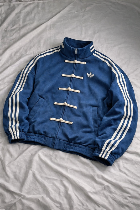 Blue Adidas jacket with white stripes on a light gray background