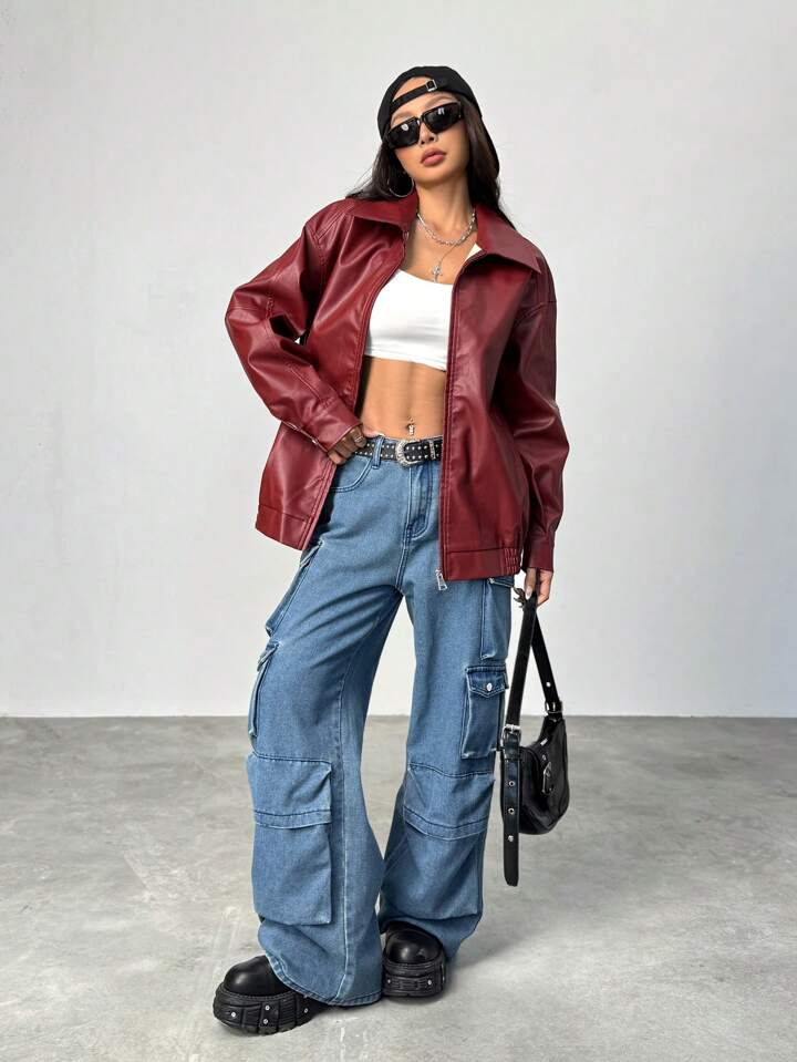 Person wearing a red leather jacket, white crop top, blue cargo pants, and black shoes on a plain background