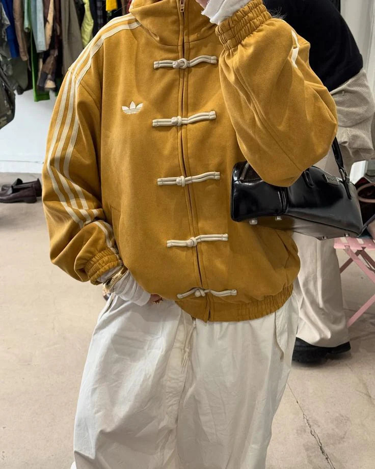 Person wearing a mustard yellow jacket with white accents in an indoor setting
