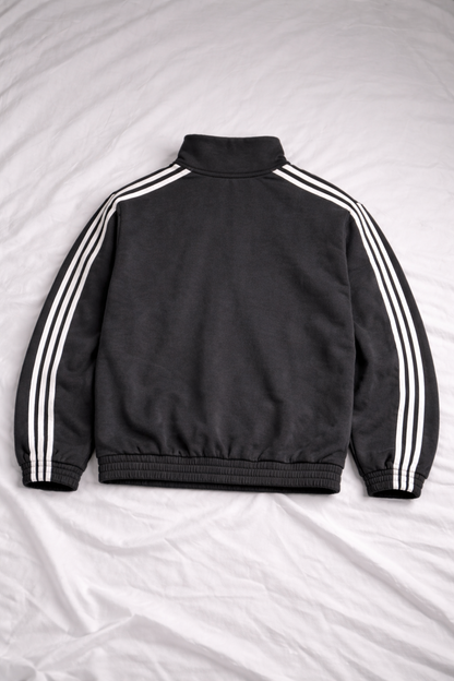 Black jacket with white stripes on sleeves and back, laid flat on a light gray surface.
